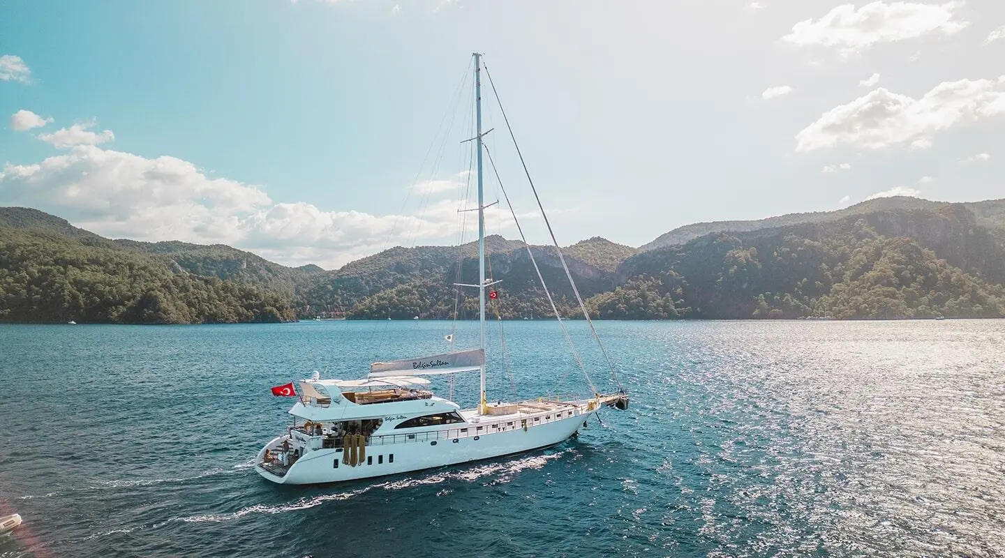 Belgin Sultan luxury gulet yacht anchored in turquoise water near hills at sunset