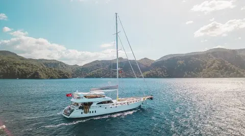 Belgin Sultan luxury gulet yacht anchored in turquoise water near hills at sunset