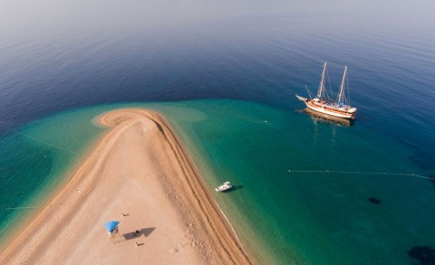 31m Tajna Mora anchored near a sandy, turquoise-channelled lagoon with a classic sailing yacht offshore