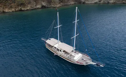 Faralya yacht anchored in calm blue water with white hull sails