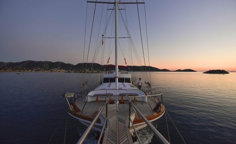 Blu Dream sailing yacht at sunset with aft deck and wide bow seating on calm blue water