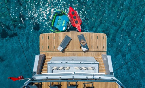 Wooden aft deck of the yacht with inflatable lifebuoy and inflatable toys tied to the water