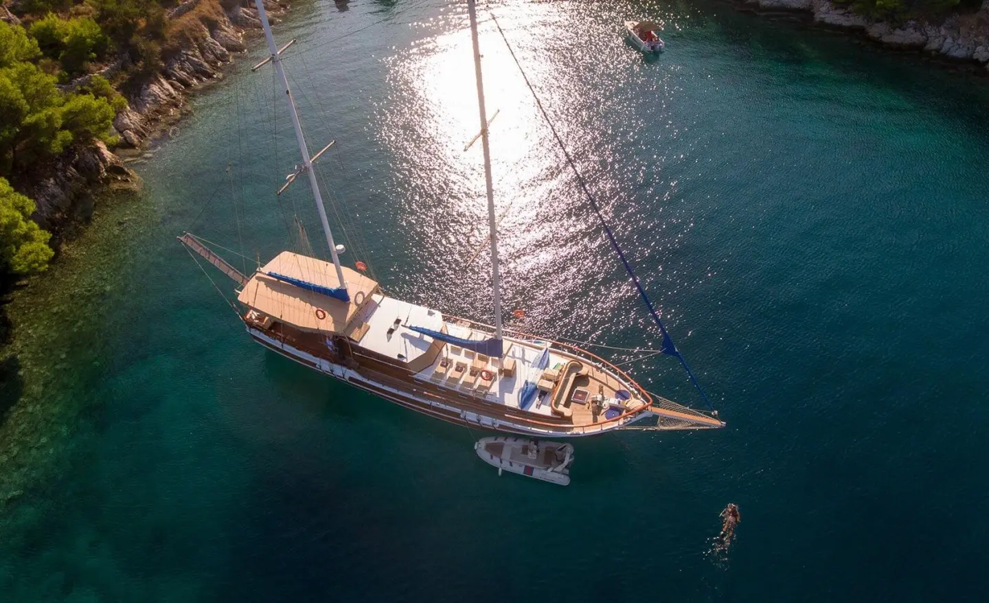 Yacht Malena anchored in calm turquoise water at sunset, warm light on deck