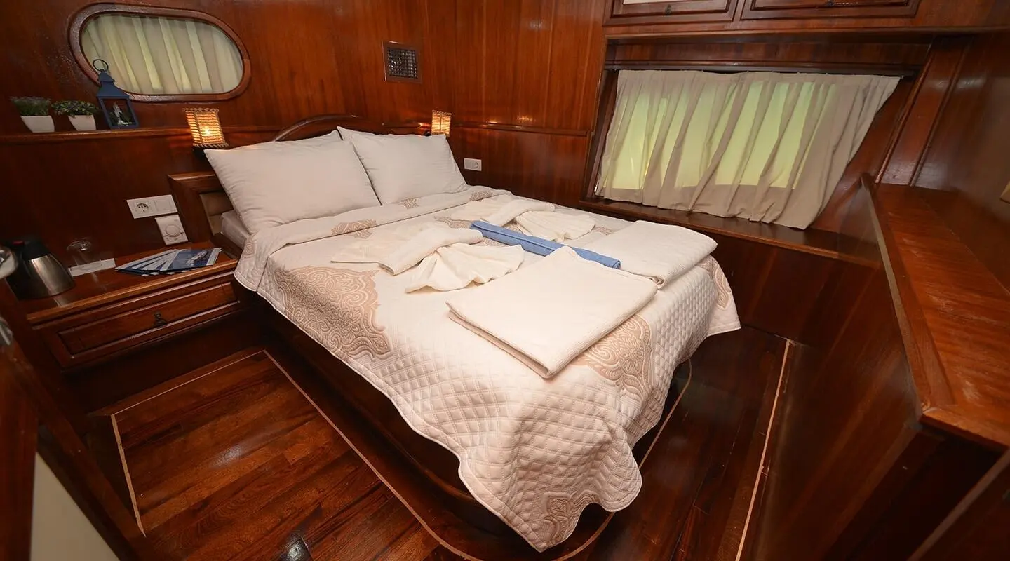 Twin bed cabin on a wooden yacht interior with striped bed linens