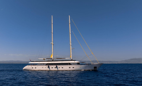 Sunset-toned luxury sailing yacht Anima Maris on calm sea foreground