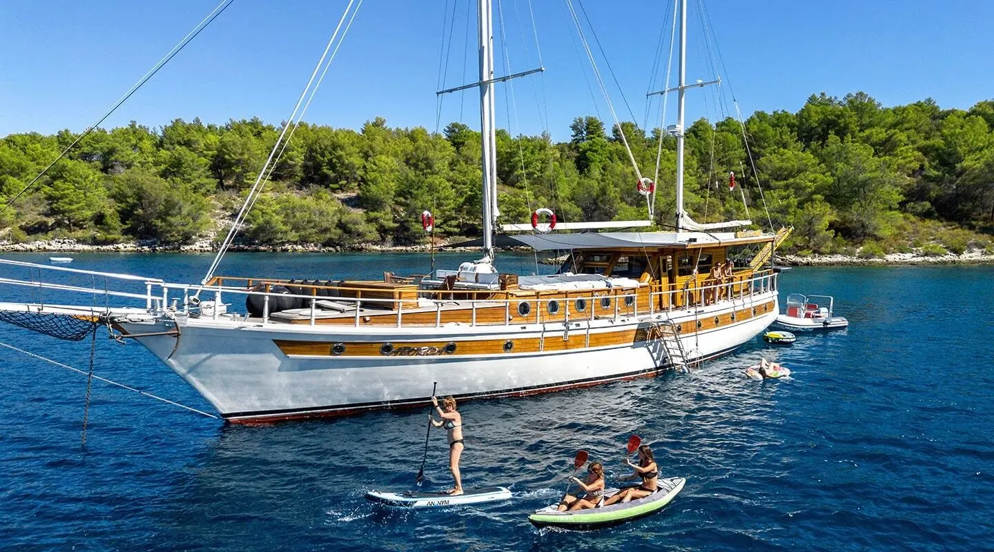 Wooden-deck yacht Aborda anchored in clear blue water