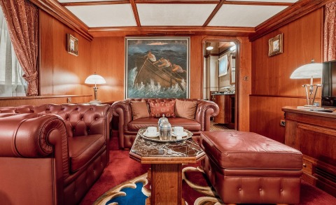 Interior of a wood-paneled red leather lounge with coffee table and sofa