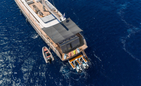 Aerial view of De Love yacht at sea with a shaded upper deck and water toys onboard