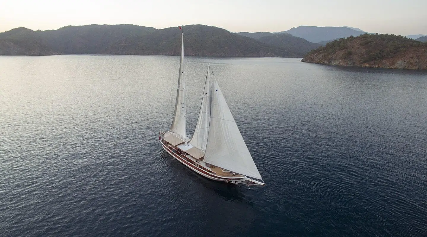 Two-masted sailing yacht on calm sea, viewed from above in a distant shot