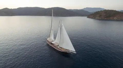 Two-masted sailing yacht on calm sea, viewed from above in a distant shot