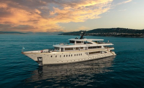 Luxurious Riva motor yacht visible on blue water with sunset-lit coastal scenery nearby