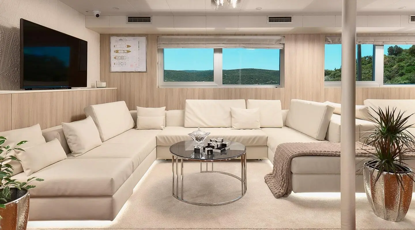 Luxurious yacht Cristal salon with cream seating and large windows overlooking sea sunset