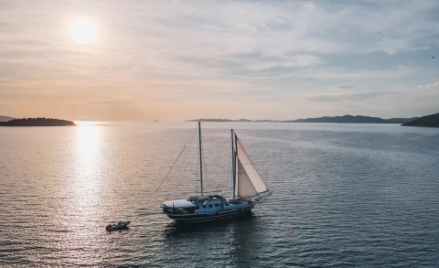Sailing gulet-style yacht on calm sea at sunset