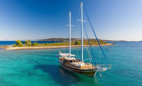 Andi Star yacht on deck with blue sea and island shore in the background