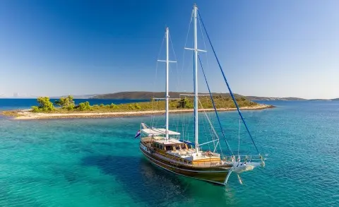 Andi Star yacht anchored in turquoise water with a sailboat under clear blue sky