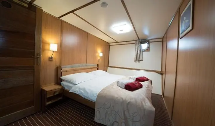 Twin beds with white linens and brown headboard in a compact yacht cabin