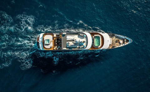 Overhead view of a luxury yacht at sea during sunset, showing deck areas and seating