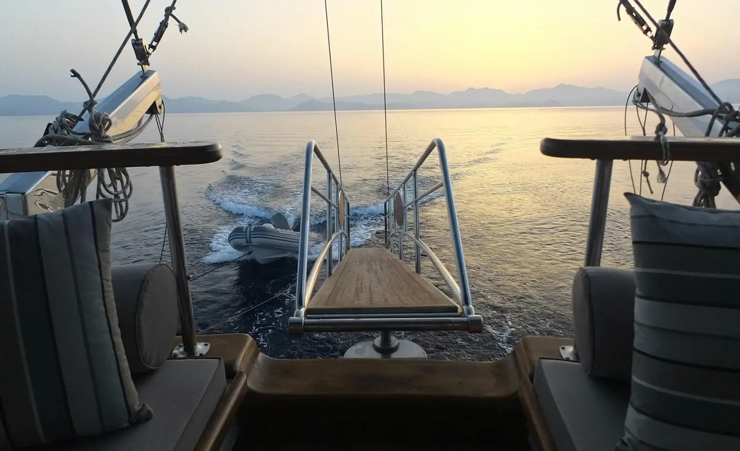Sunset view from deck of a luxury gulet, calm sea and railing visible