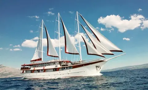 Amorena luxury sailing yacht with multiple white sails near blue sea