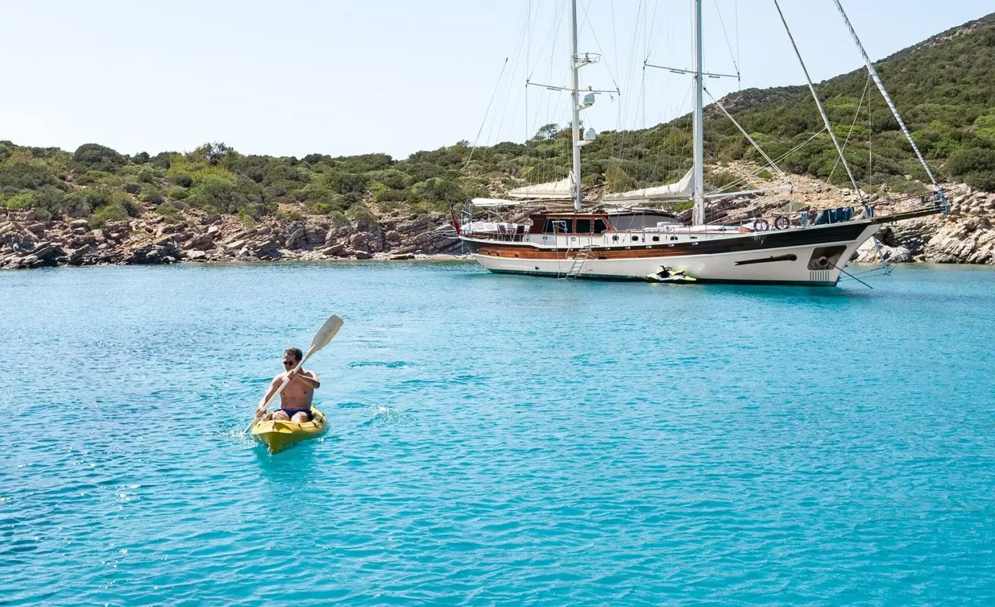 Yacht Estrella De Mar anchored in turquoise bay with moored boats ashore