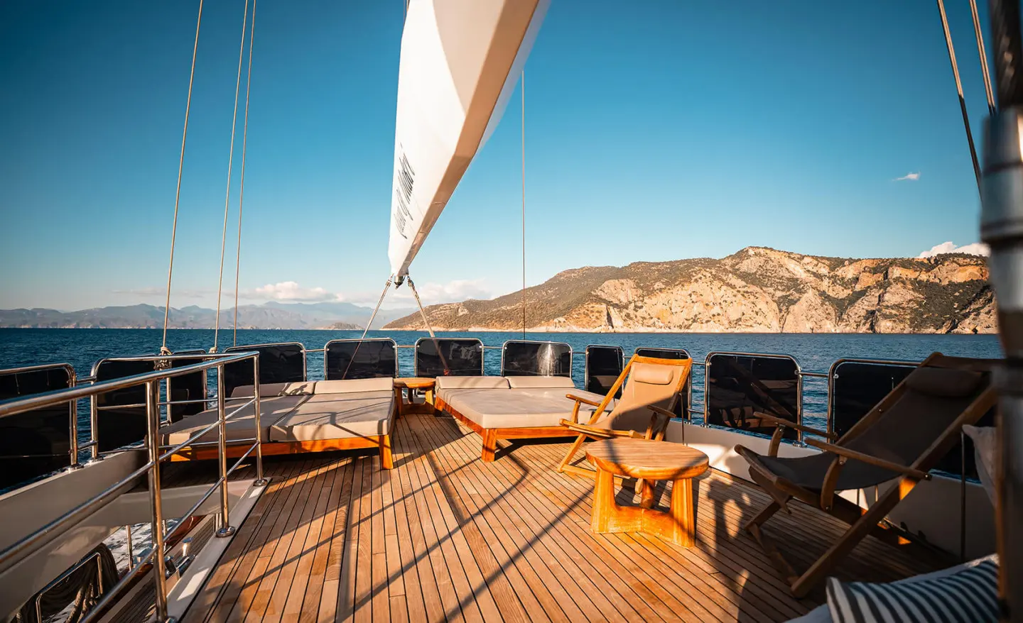 Gulet Queen Of Makri deck with sails raised and spacious wooden dining area