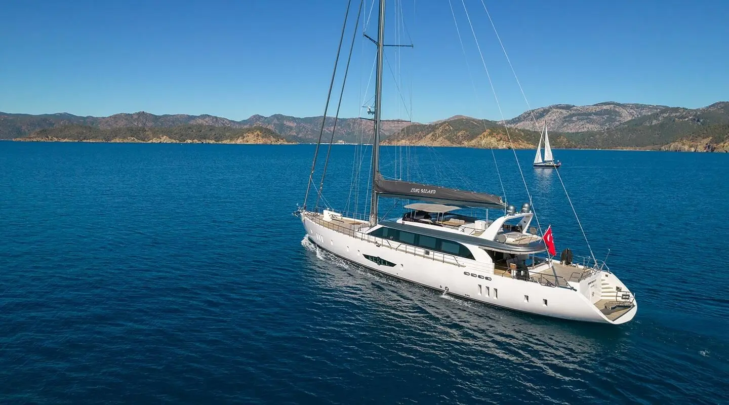 Long Island yacht with white hull anchored in calm blue sea at sunset