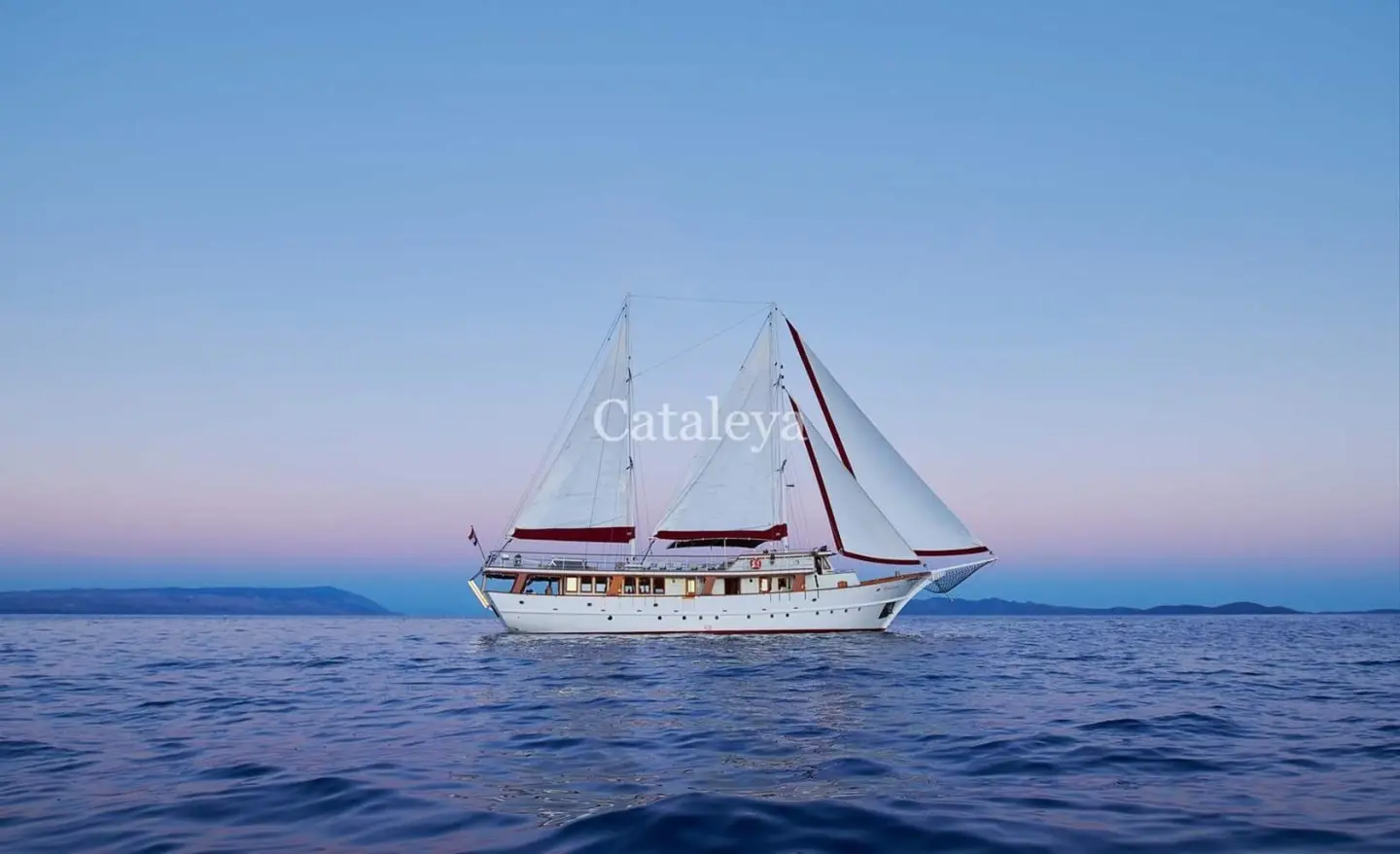 Yacht Cataleya gulet sailing on calm sea with sails unfurled at sunset