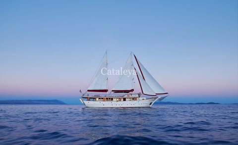 Sailing gulet yacht on calm sea, white sails open against blue sky
