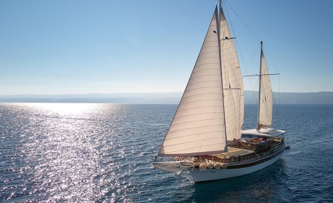 Luxury sailing yacht with two white sails on calm sea at sunset