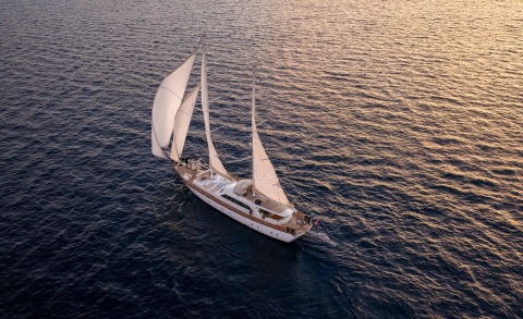 Luxury sailing yacht with multiple masts sailing on sea at sunset
