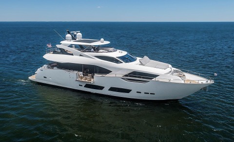White yacht Quantum anchored in open sea with a spacious upper deck and portholes along the hull