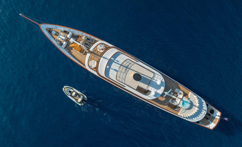 Aerial top-down view of Maia yacht with wooden deck and white superstructure in blue sea