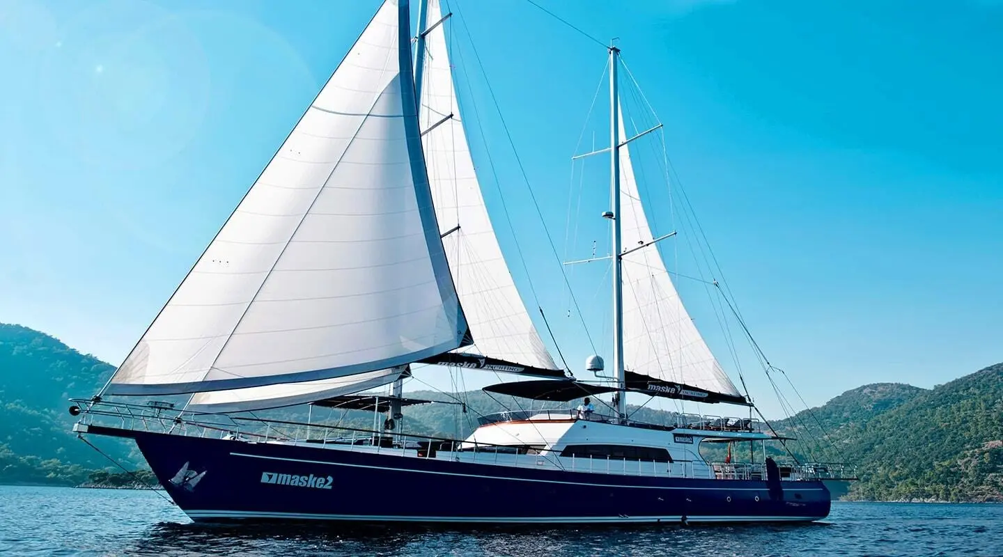 Maske 2 yacht sailing with white sails on calm blue sea at sunset