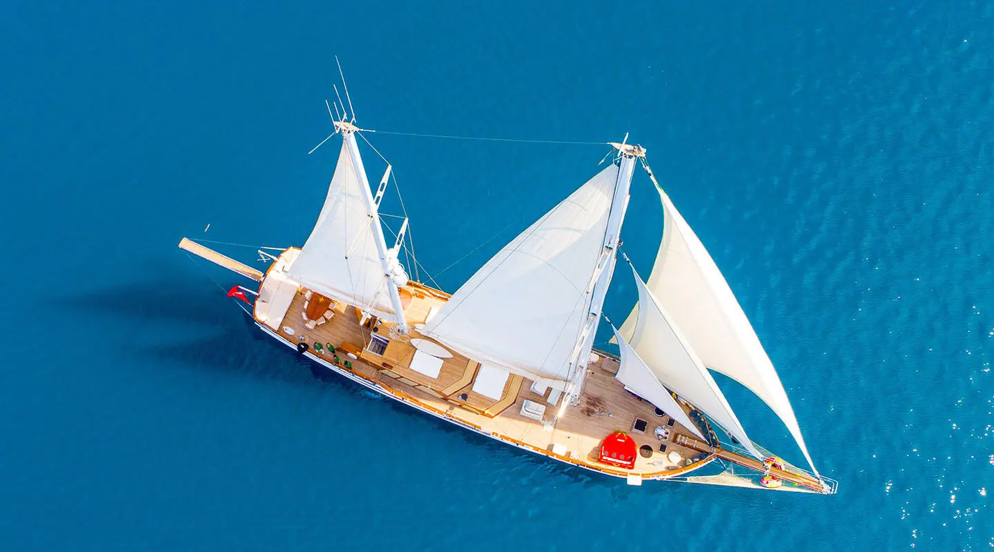 Grande Mare yacht sailing with white sails on blue sea at sunset
