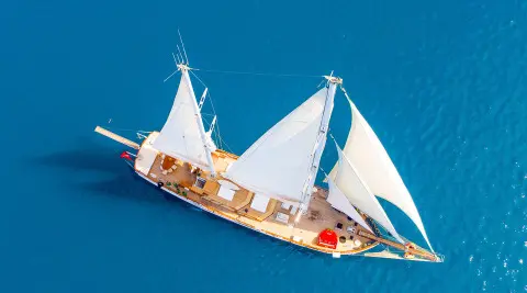 Grande Mare yacht sailing with white sails on blue sea at sunset