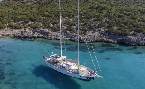 Gazella sailing yacht anchored in clear blue water near rocky shore