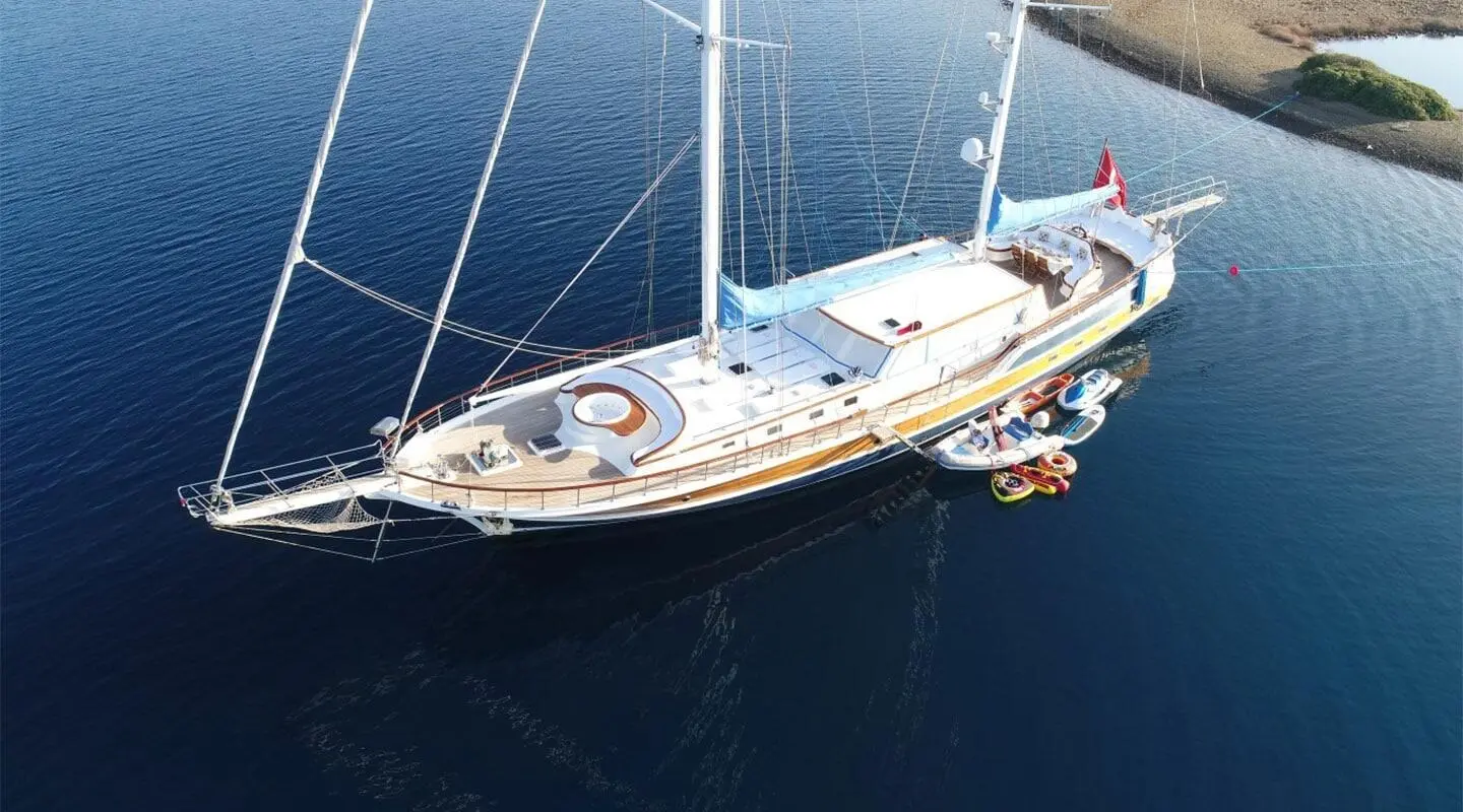 A sleek white sailing yacht named Ece Berrak moored in calm blue water at sunset