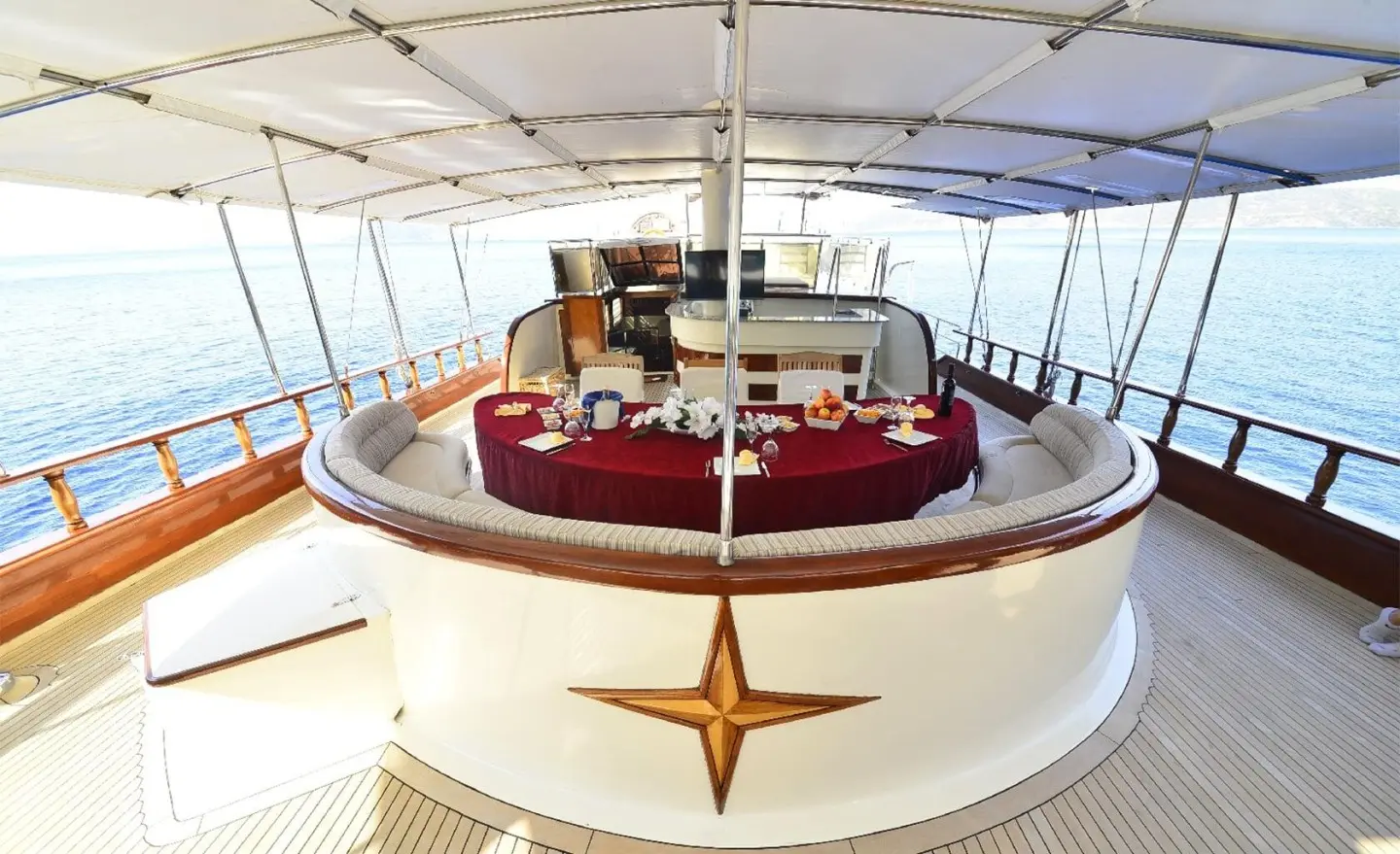 Front view of Berrak Su yacht with sunlit deck and red seating under canopy