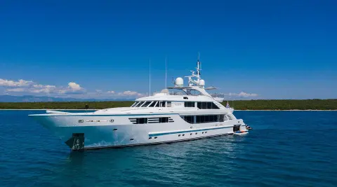 Alalya luxury motor yacht anchored offshore with clear blue water and a distant coastline