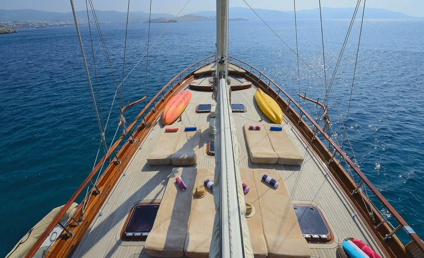 Sunset-lit yacht Samarkand bow with wooden deck and ropes on calm sea