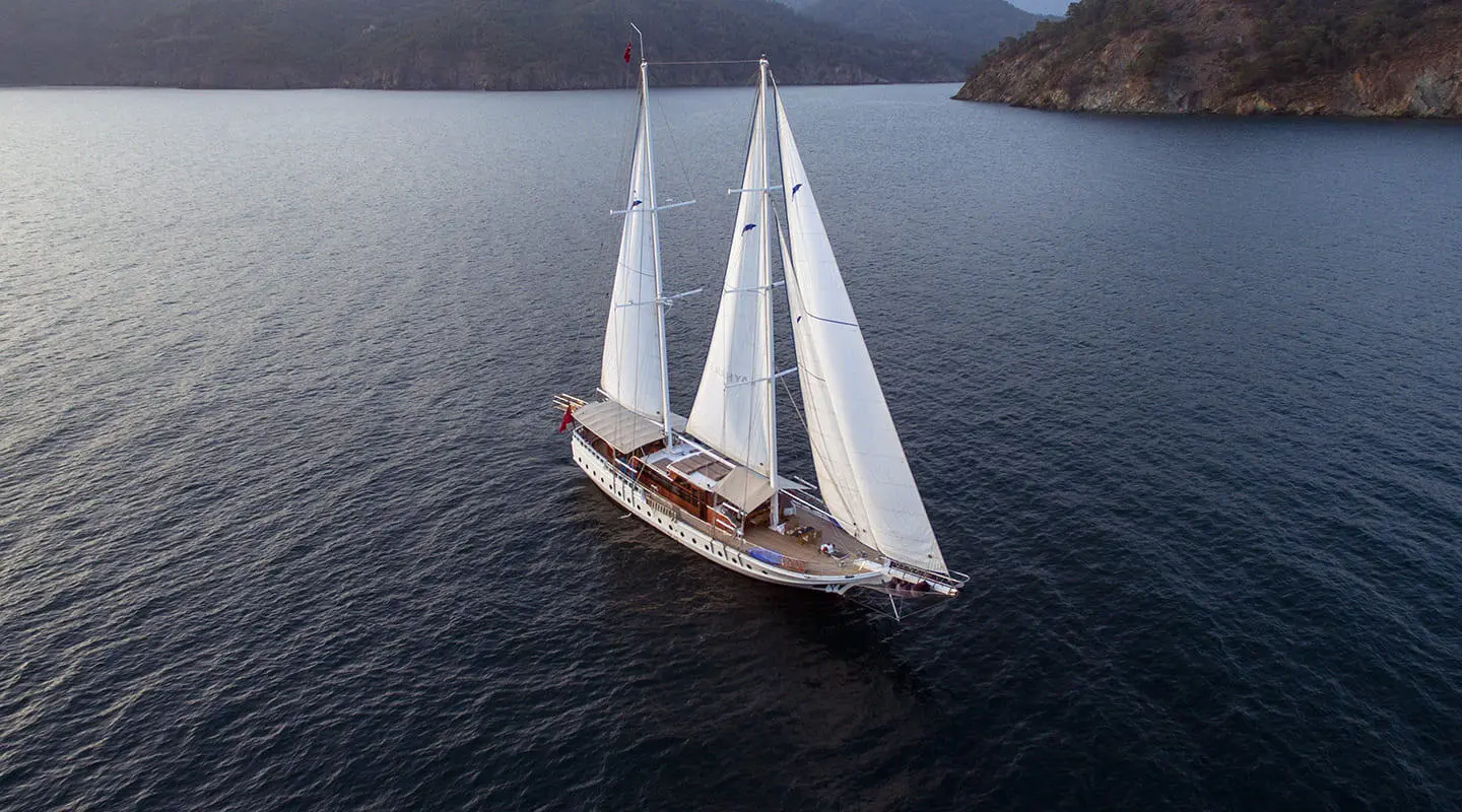 Aerial view of Kayhan 5 gulet sailing in calm blue water near rocky coastline