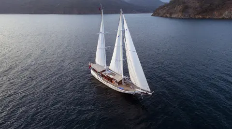 Aerial view of Kayhan 5 gulet sailing in calm blue water near rocky coastline
