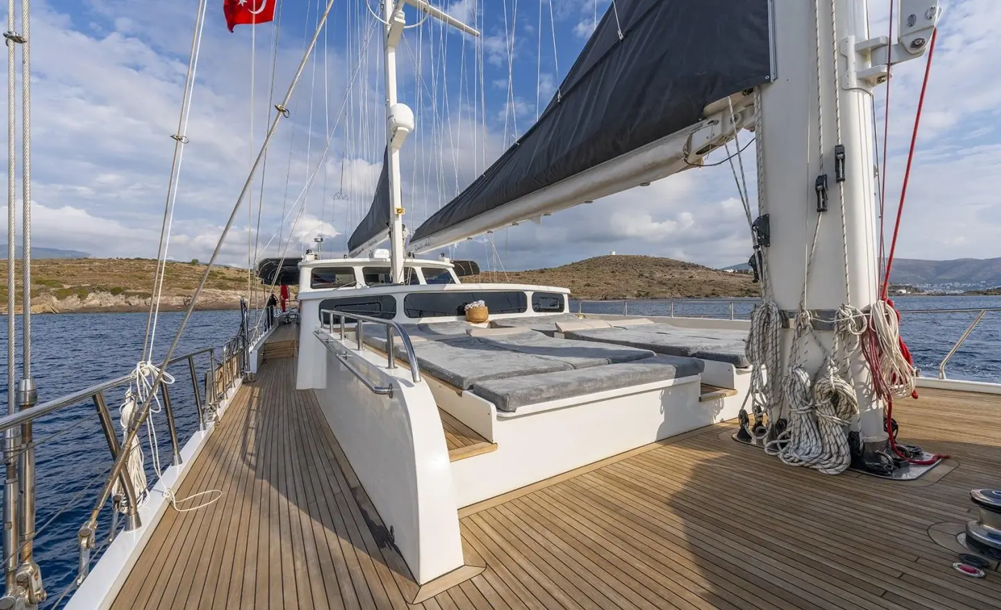Luxurious yacht deck with wooden flooring and sails at sunset