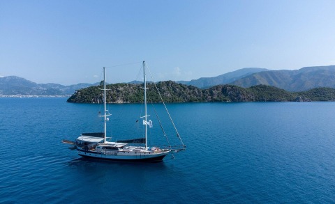 Derya Deniz sailing yacht anchored in blue calm sea with rocky island backdrop
