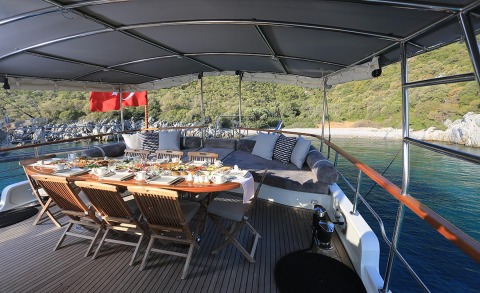 Open deck with a long dining table set for a meal on a yacht