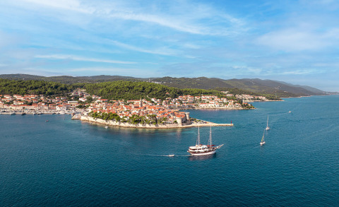 Cesarica gulet sailing in open sea near coastal village and green hills