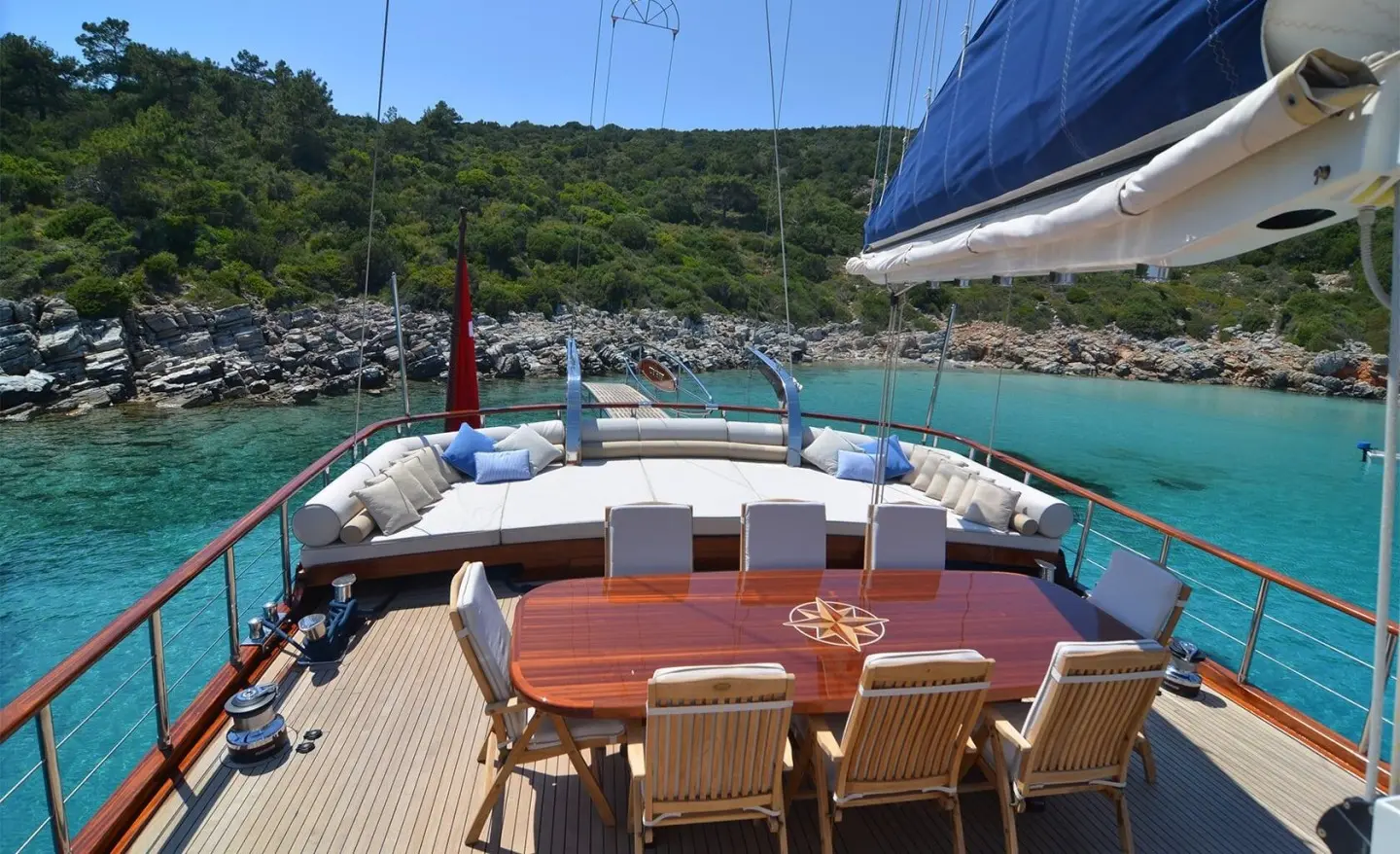 Blue Heaven yacht; sunlit deck with cushioned seating and blue canopy at sunset