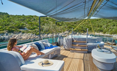 Rara Avis yacht deck with sun loungers, cushions, shaded area, and sea view