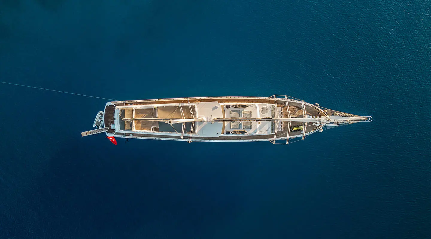 Top-down view of a luxury gulet anchored on blue sea at sunset