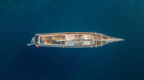 Top-down view of a luxury gulet anchored on blue sea at sunset